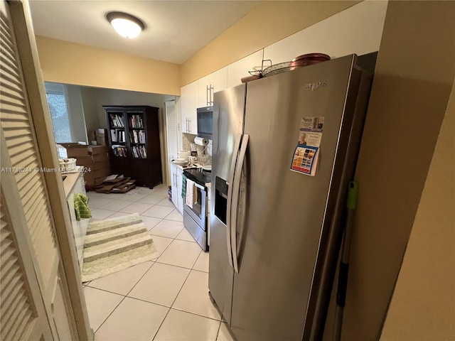 kitchen featuring white cabinets, appliances with stainless steel finishes, and light tile patterned flooring