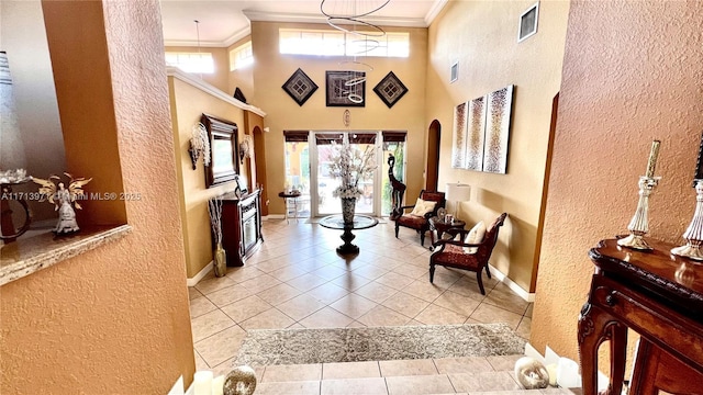 corridor with light tile patterned floors, ornamental molding, and a high ceiling