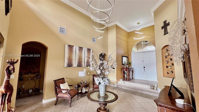 tiled entryway with a towering ceiling and ornamental molding