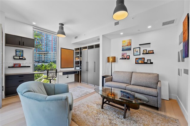 living room with a wall of windows and light hardwood / wood-style flooring