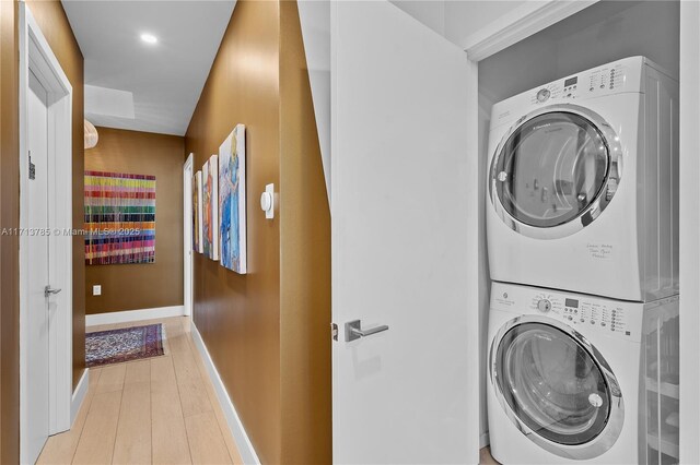 laundry area featuring stacked washing maching and dryer and light hardwood / wood-style flooring