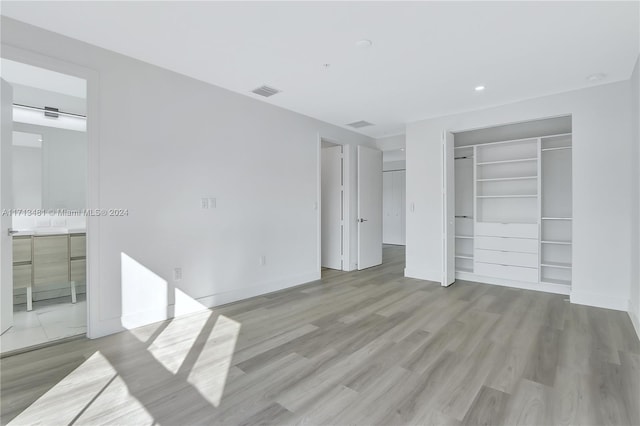 unfurnished bedroom featuring ensuite bath and light hardwood / wood-style flooring