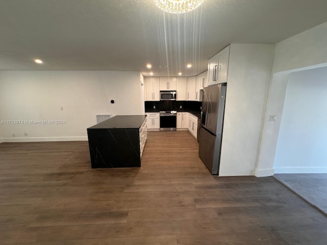 kitchen with backsplash, stainless steel appliances, dark wood-type flooring, a center island, and white cabinetry