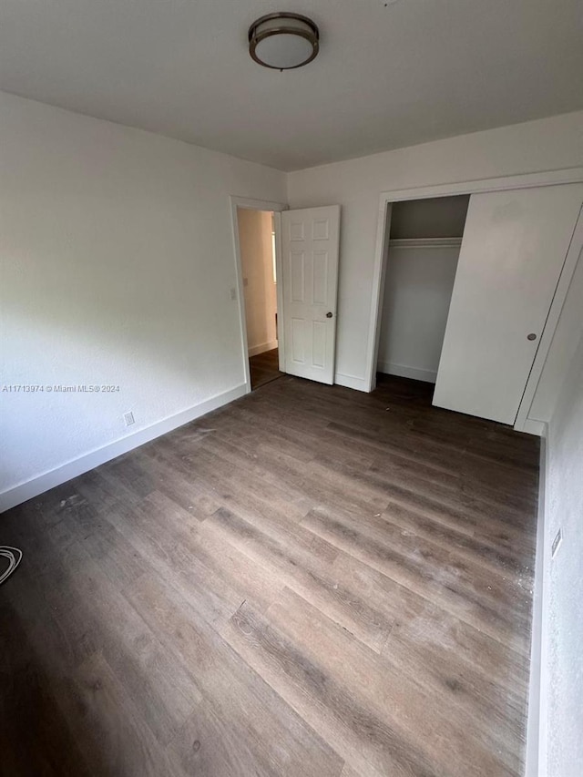 unfurnished bedroom with dark wood-type flooring and a closet