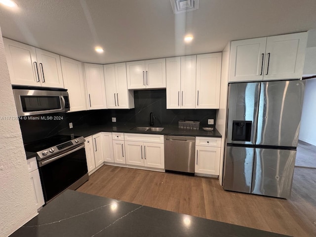 kitchen with stainless steel appliances, white cabinetry, and sink