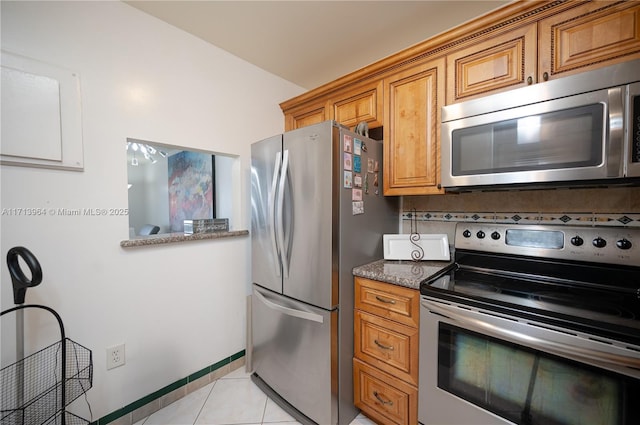 kitchen with tasteful backsplash, stone counters, light tile patterned flooring, and appliances with stainless steel finishes