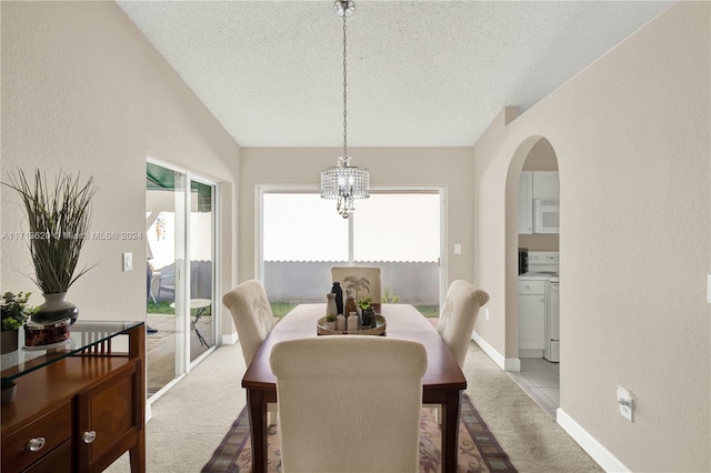 carpeted dining room with a textured ceiling and an inviting chandelier