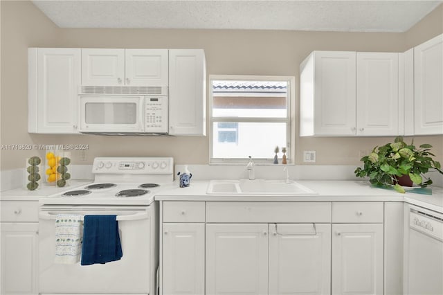 kitchen featuring a textured ceiling, white cabinetry, white appliances, and sink