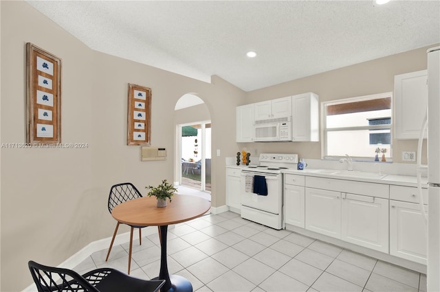 kitchen featuring light tile patterned flooring, white appliances, white cabinetry, and sink