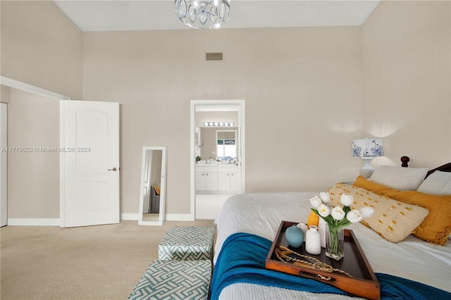 bedroom with ensuite bathroom, light colored carpet, and a towering ceiling