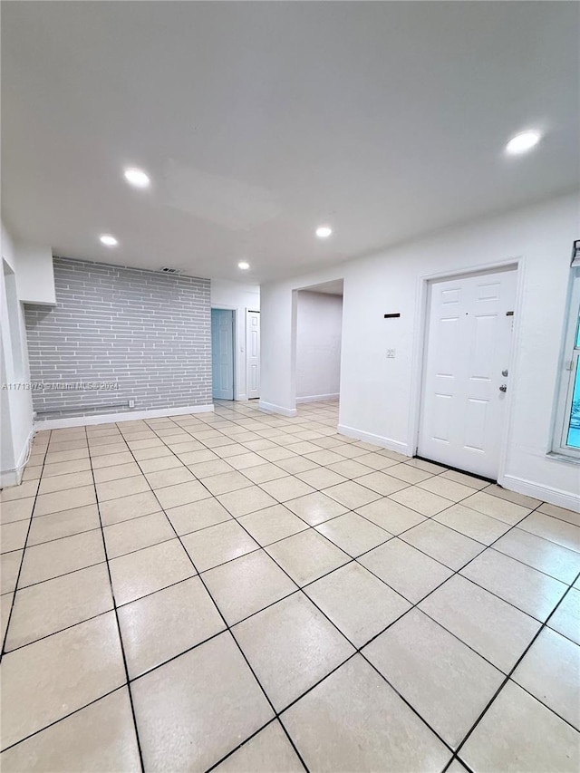 basement with brick wall and light tile patterned flooring