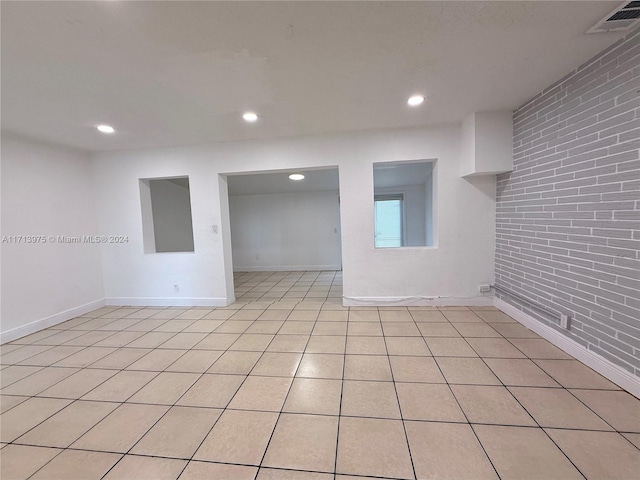 tiled spare room featuring brick wall