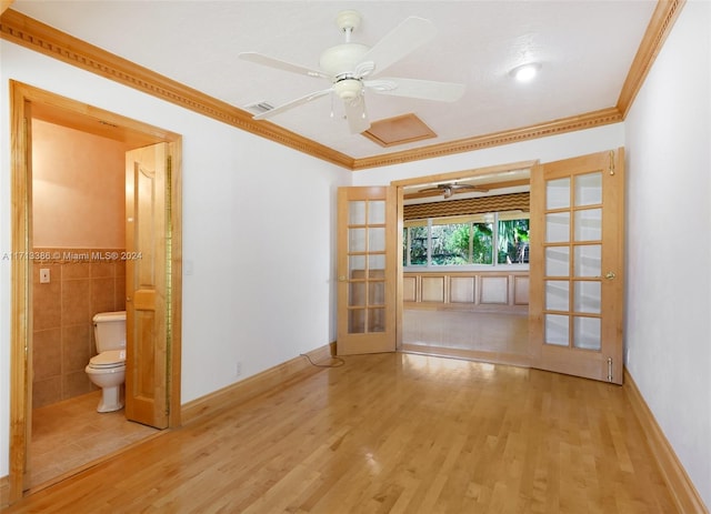 unfurnished living room with crown molding, light wood-type flooring, tile walls, and french doors