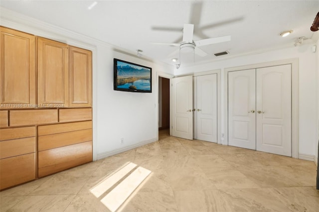 unfurnished bedroom featuring two closets, ceiling fan, and ornamental molding