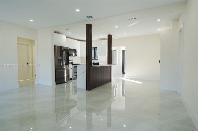 kitchen featuring tasteful backsplash, white cabinetry, a kitchen island, and appliances with stainless steel finishes