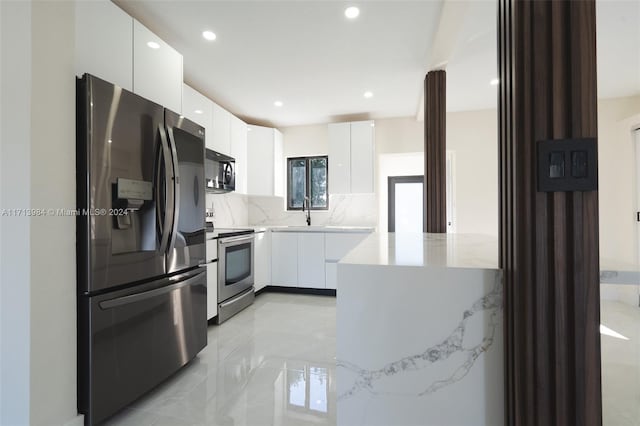 kitchen featuring stainless steel appliances, white cabinetry, tasteful backsplash, and sink