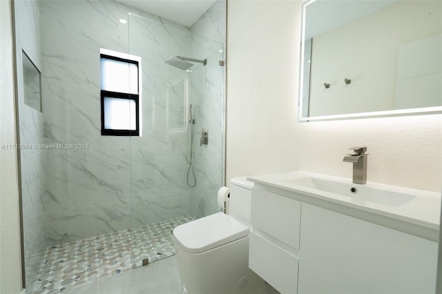 bathroom featuring a tile shower, vanity, and toilet