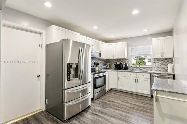 kitchen featuring sink, light wood-type flooring, appliances with stainless steel finishes, tasteful backsplash, and white cabinetry