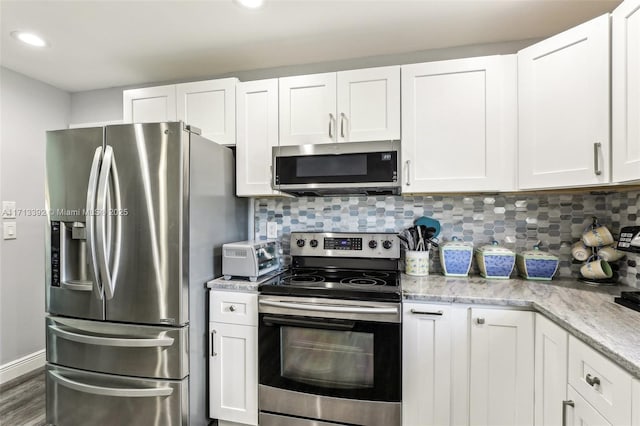 kitchen featuring stainless steel appliances, white cabinetry, and backsplash