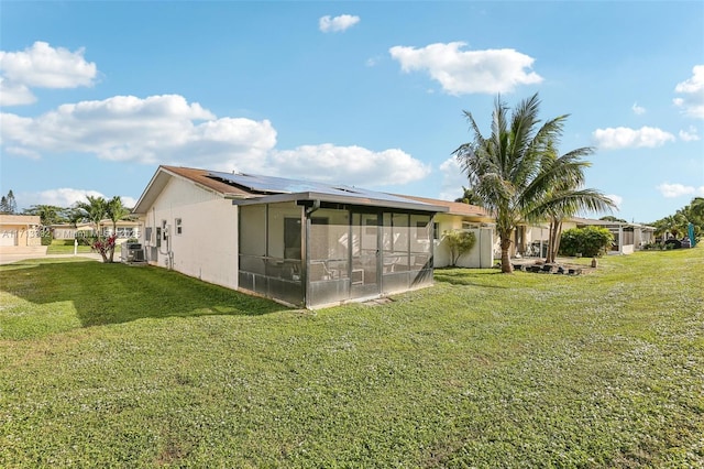 back of house featuring solar panels, a yard, central AC unit, and a sunroom