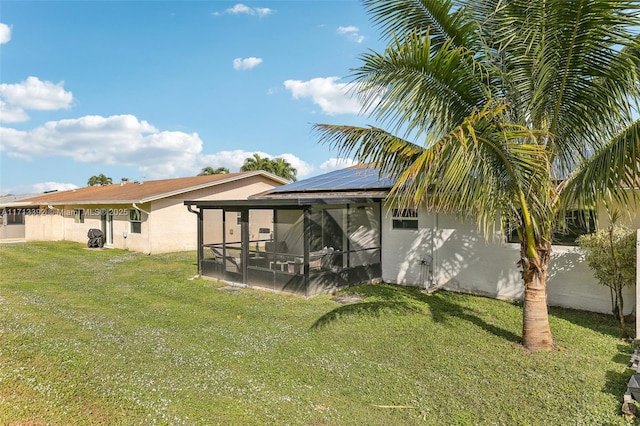 back of house with a lawn, solar panels, and a sunroom