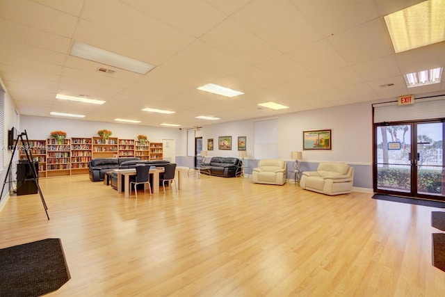 interior space with light wood-type flooring, french doors, and a paneled ceiling