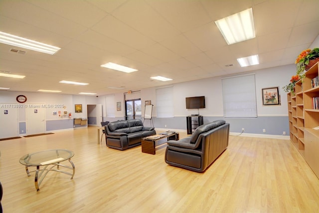 living room featuring light hardwood / wood-style flooring and a drop ceiling