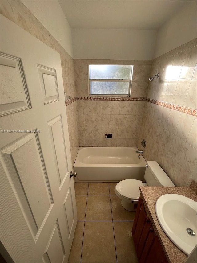 full bathroom with vanity, tiled shower / bath, tile patterned flooring, toilet, and tile walls