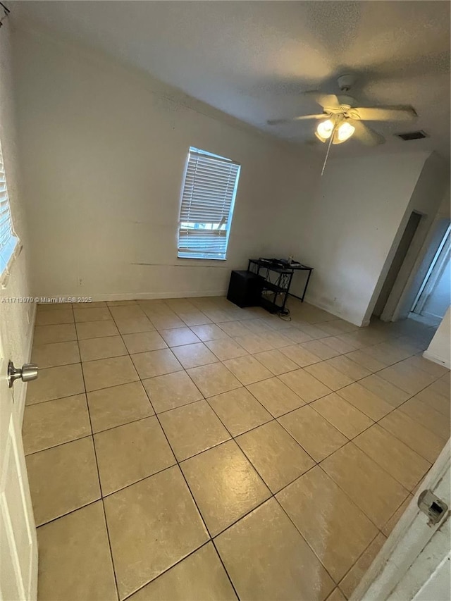 tiled empty room featuring ceiling fan