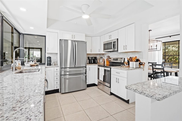 kitchen with light stone countertops, sink, stainless steel appliances, and white cabinetry