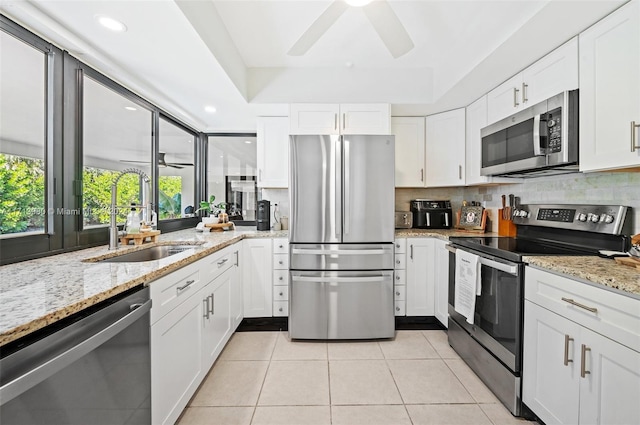 kitchen featuring light tile patterned flooring, sink, white cabinetry, light stone countertops, and stainless steel appliances