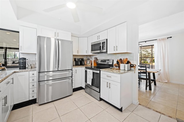 kitchen featuring light stone countertops, appliances with stainless steel finishes, white cabinetry, ceiling fan, and light tile patterned floors