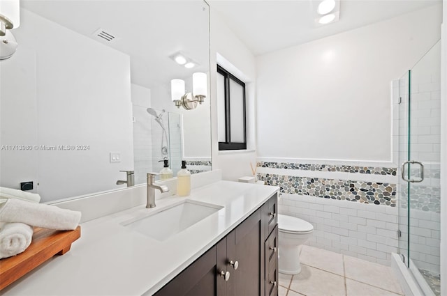 bathroom with toilet, vanity, tile patterned flooring, tile walls, and an enclosed shower