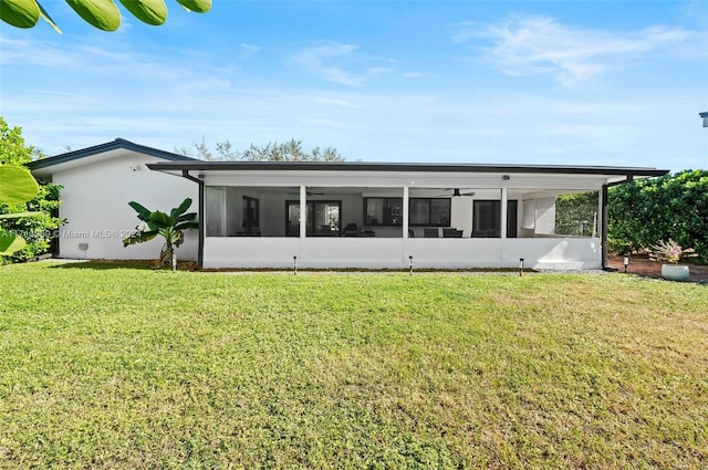 rear view of house featuring a sunroom and a lawn