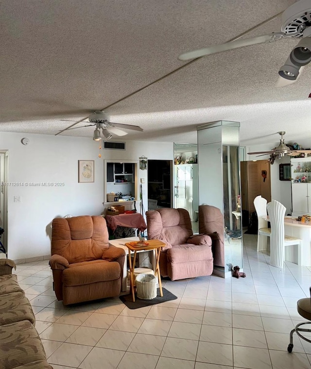 living room with light tile patterned floors, a textured ceiling, and ceiling fan