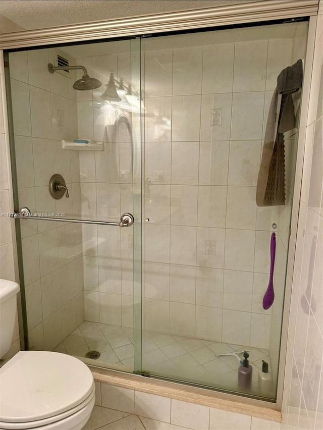 bathroom featuring tile patterned floors, a shower with door, and toilet