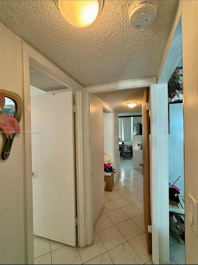 corridor with light tile patterned flooring and a textured ceiling