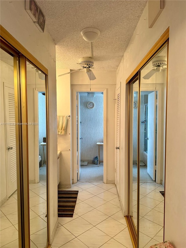 hall with a textured ceiling and light tile patterned floors