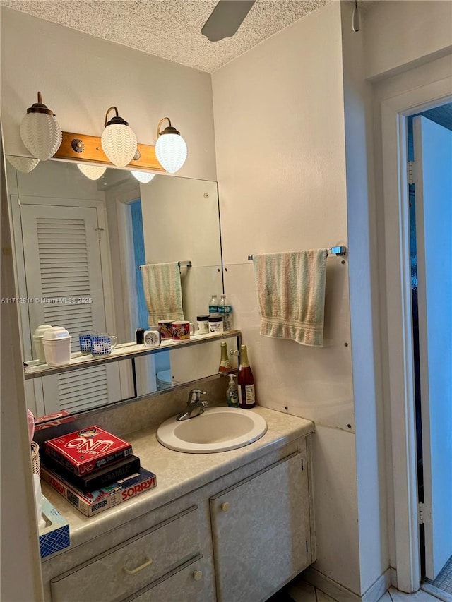 bathroom with ceiling fan, vanity, and a textured ceiling