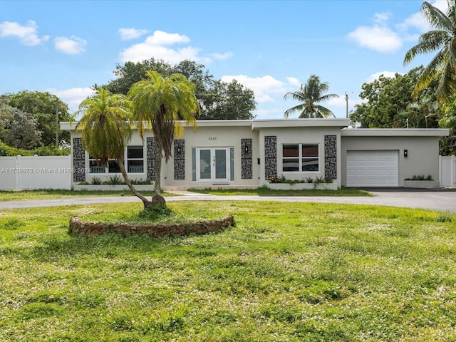 view of front of property with stucco siding, fence, a garage, driveway, and a front lawn