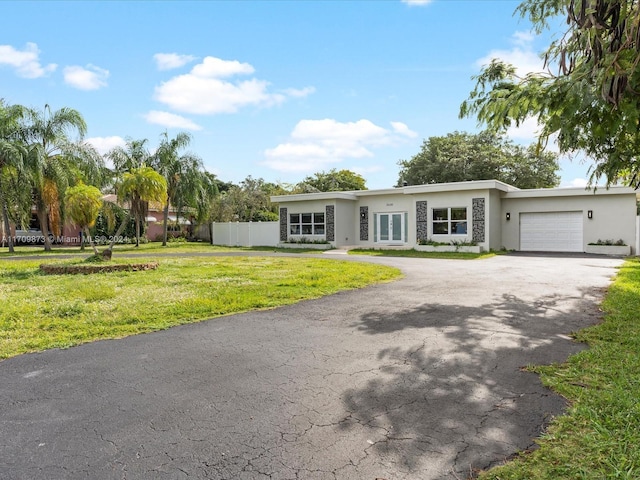 view of front of home with aphalt driveway, a garage, fence, stucco siding, and a front lawn