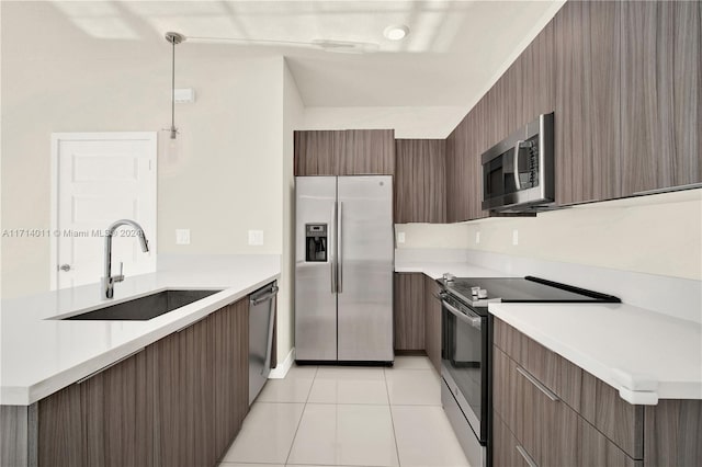 kitchen featuring light tile patterned flooring, decorative light fixtures, stainless steel appliances, and sink