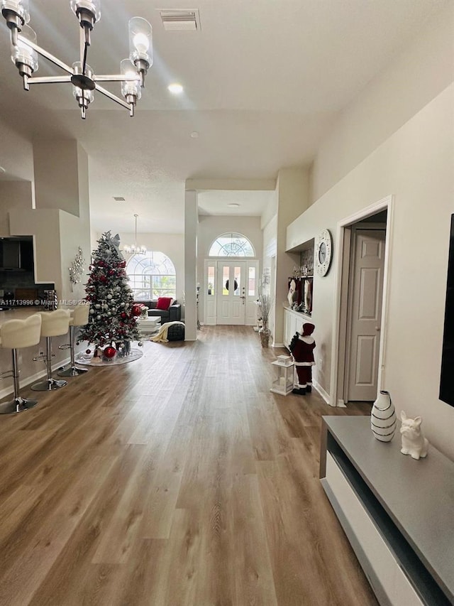 hallway with wood-type flooring and an inviting chandelier