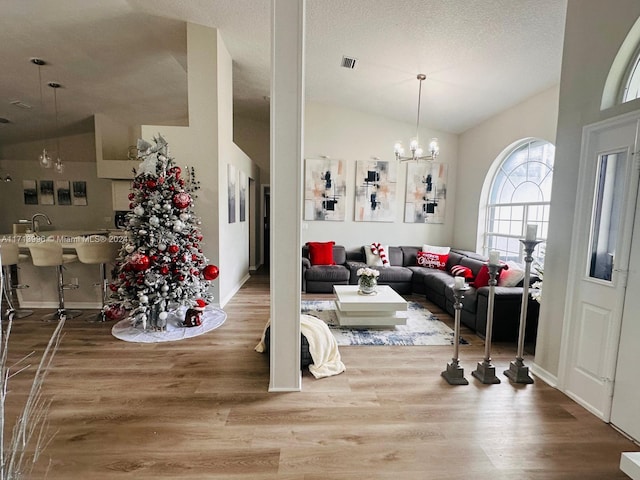 living room featuring hardwood / wood-style flooring, a notable chandelier, and vaulted ceiling