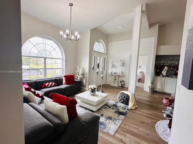 living room with a wealth of natural light, hardwood / wood-style floors, a textured ceiling, and an inviting chandelier