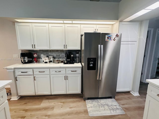 kitchen featuring white cabinets, decorative backsplash, light hardwood / wood-style floors, and stainless steel fridge with ice dispenser