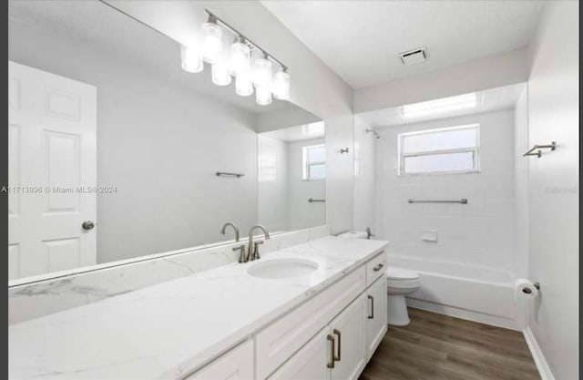 full bathroom with hardwood / wood-style floors, vanity, toilet, and tiled shower / bath combo