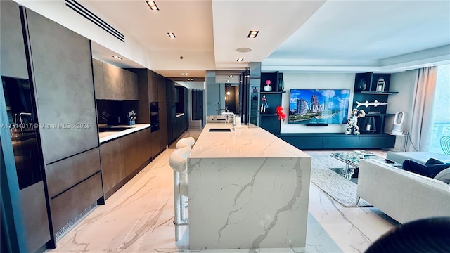 interior space with light stone countertops, sink, and an island with sink