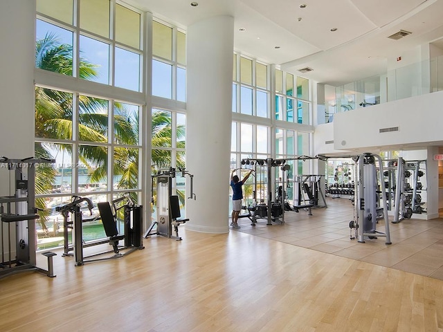 workout area with light wood-type flooring and a high ceiling