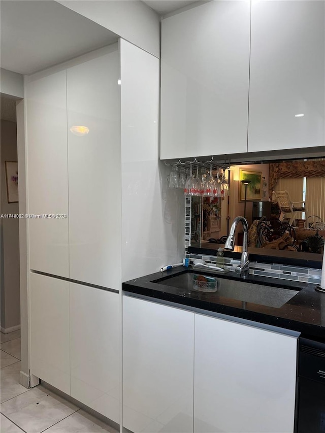 kitchen with dark stone counters, sink, white cabinets, and light tile patterned flooring